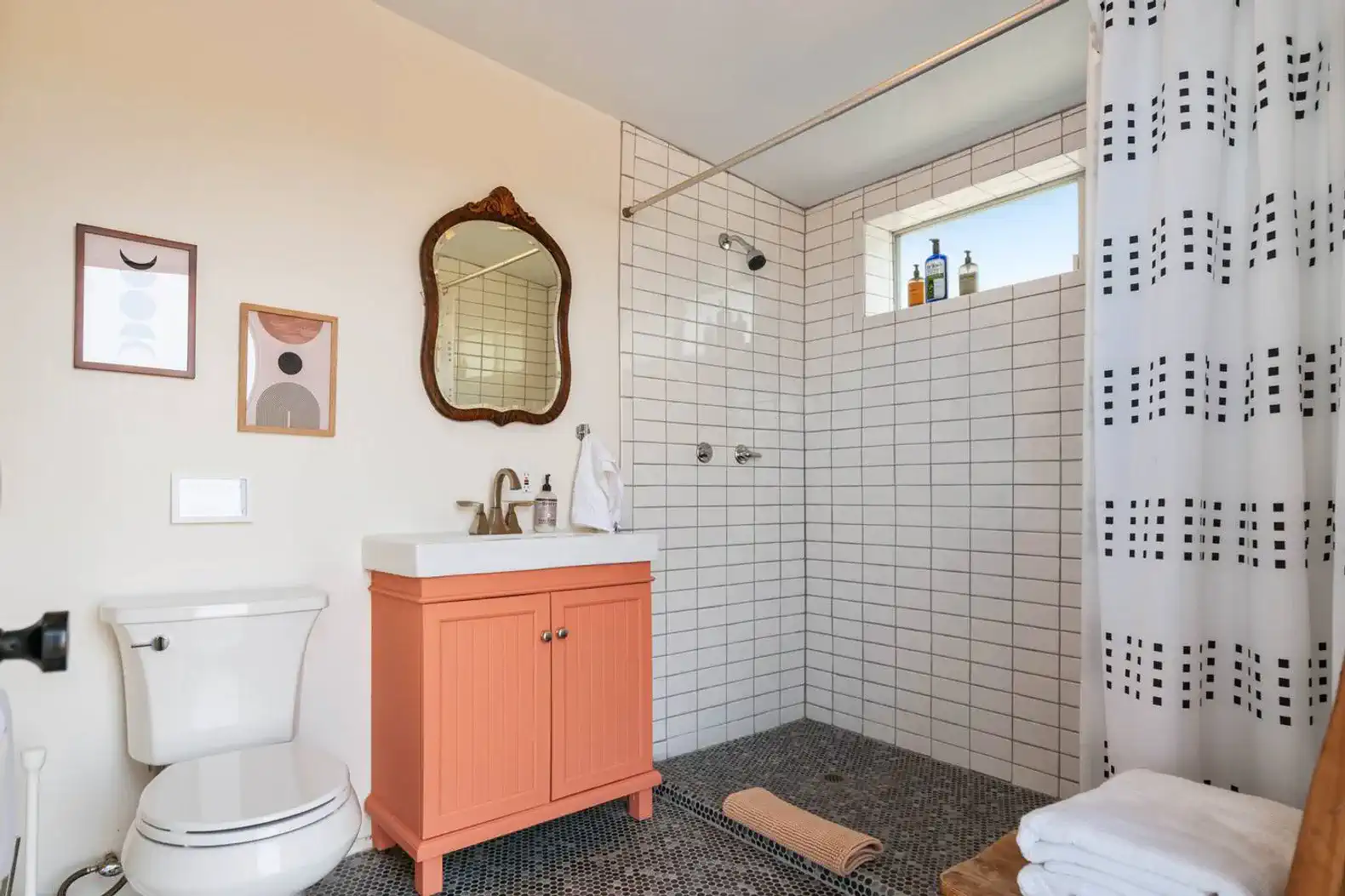 Modern bathroom with orange vanity, tiled shower, and decorative wall art