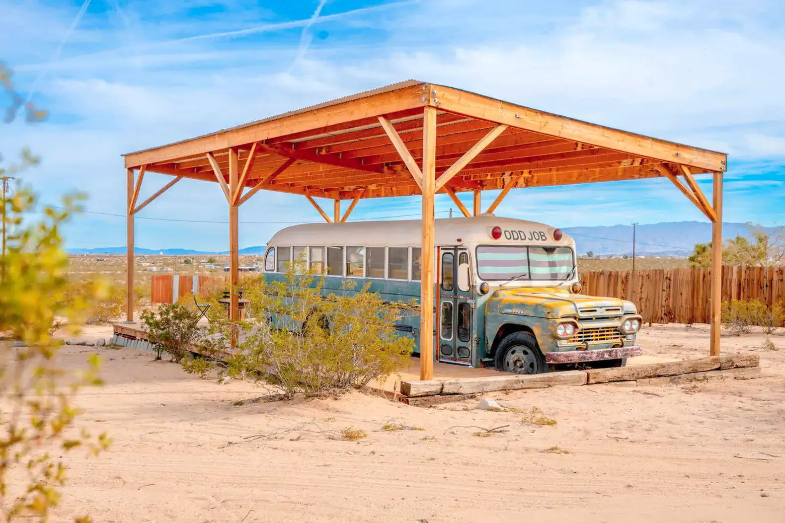 Vintage bus under a wooden shelter in a desert landscape