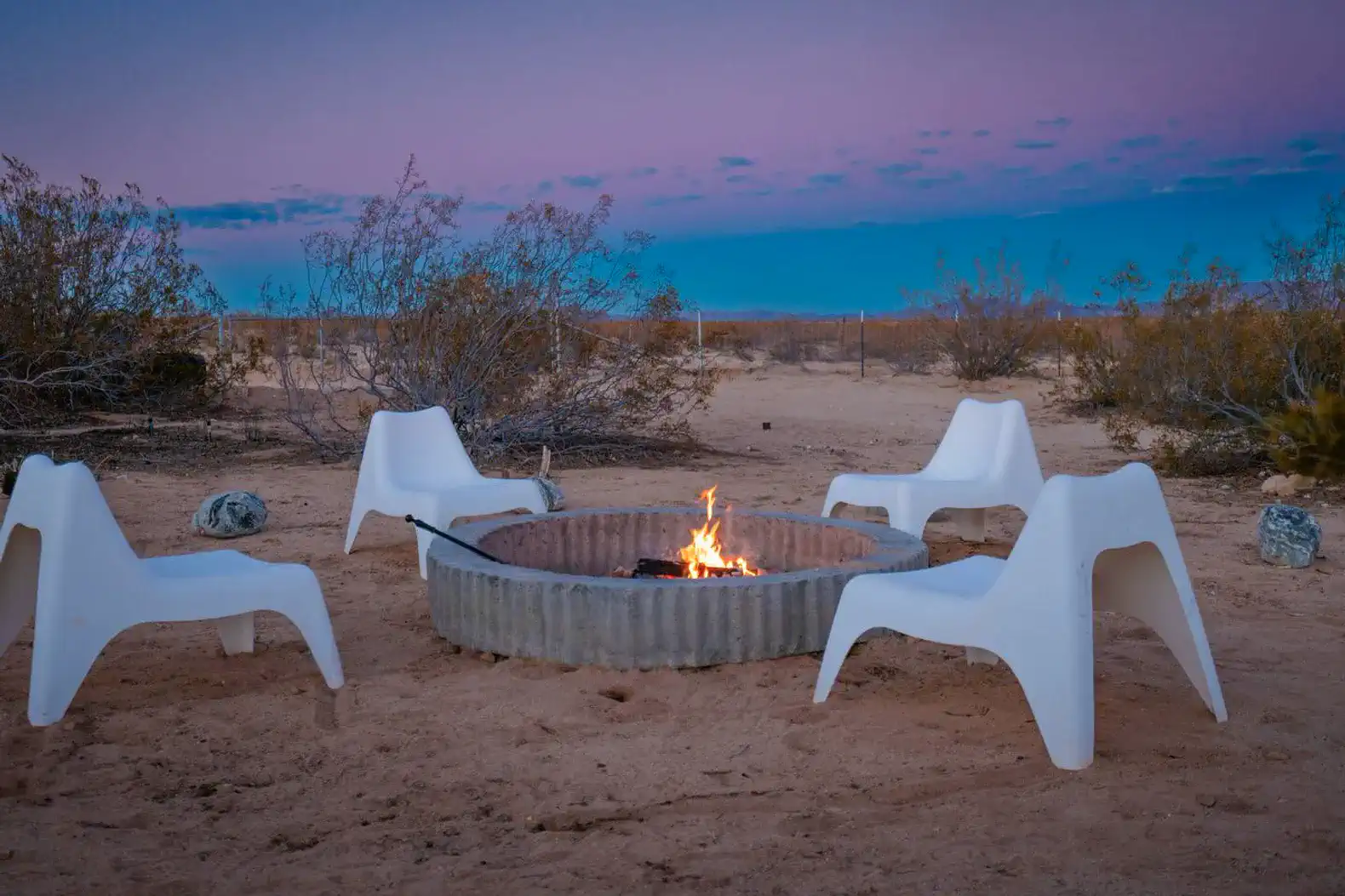 Cozy fire pit area with white chairs surrounded by desert landscape