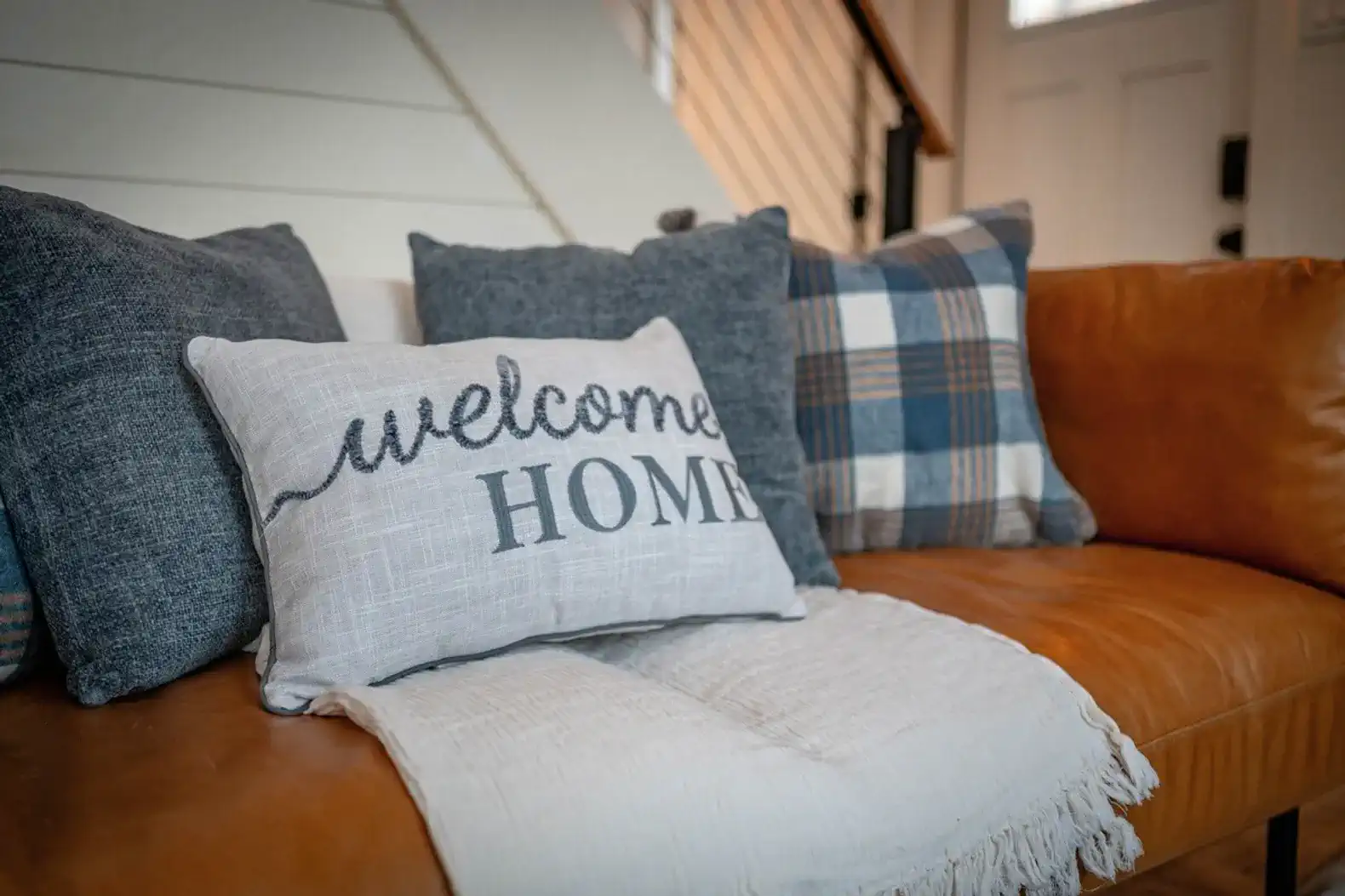 Cozy couch with decorative pillows and a welcome home message