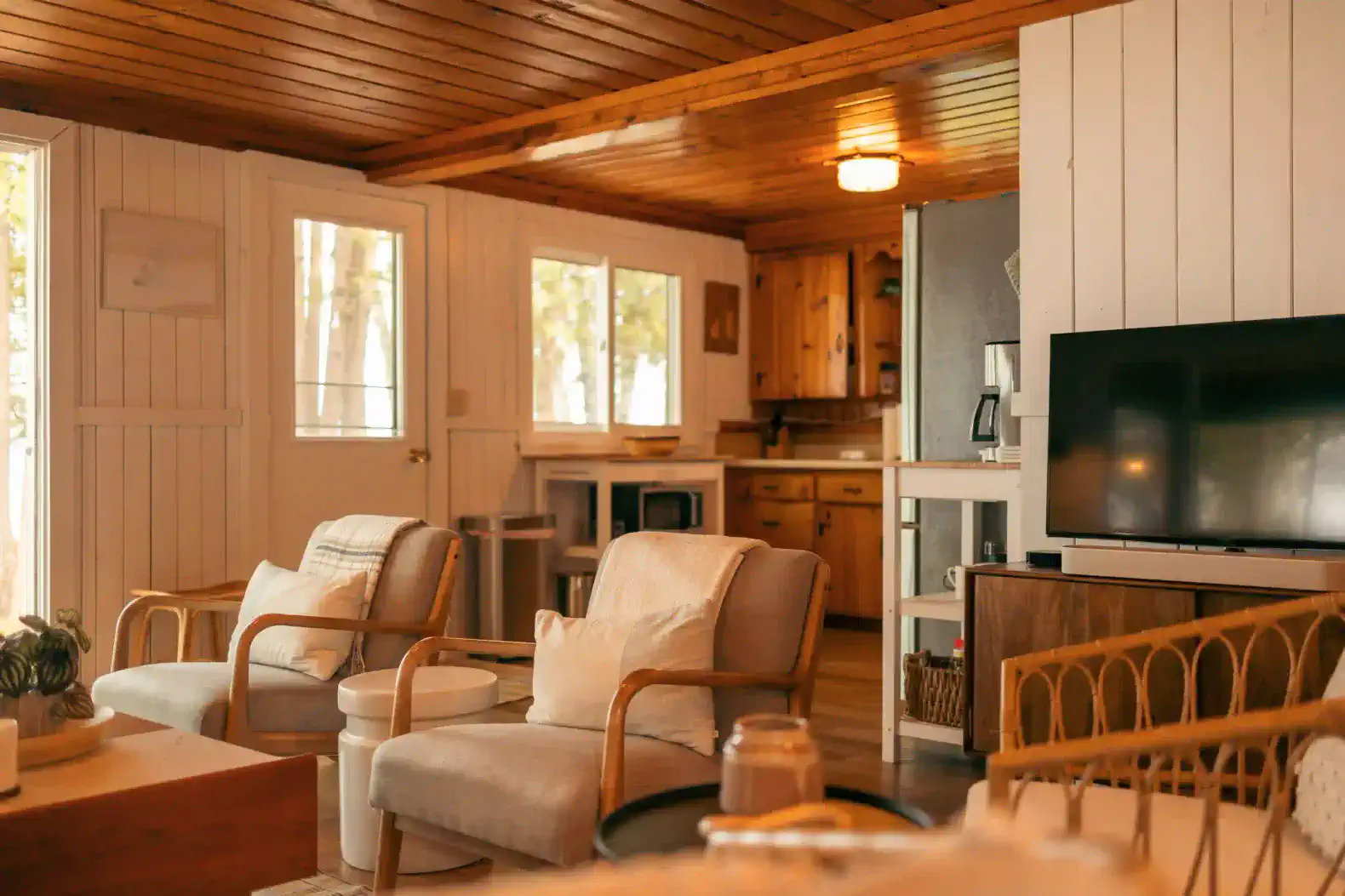 Cozy living room with wooden ceiling, comfortable seating, and open kitchen view