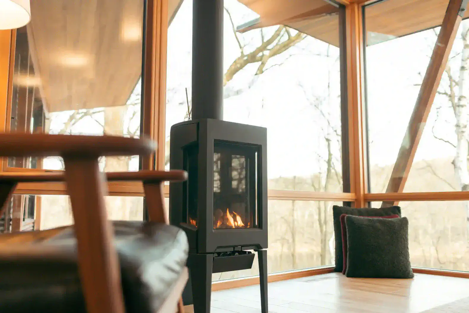 Cozy fireplace with modern design and large windows overlooking nature