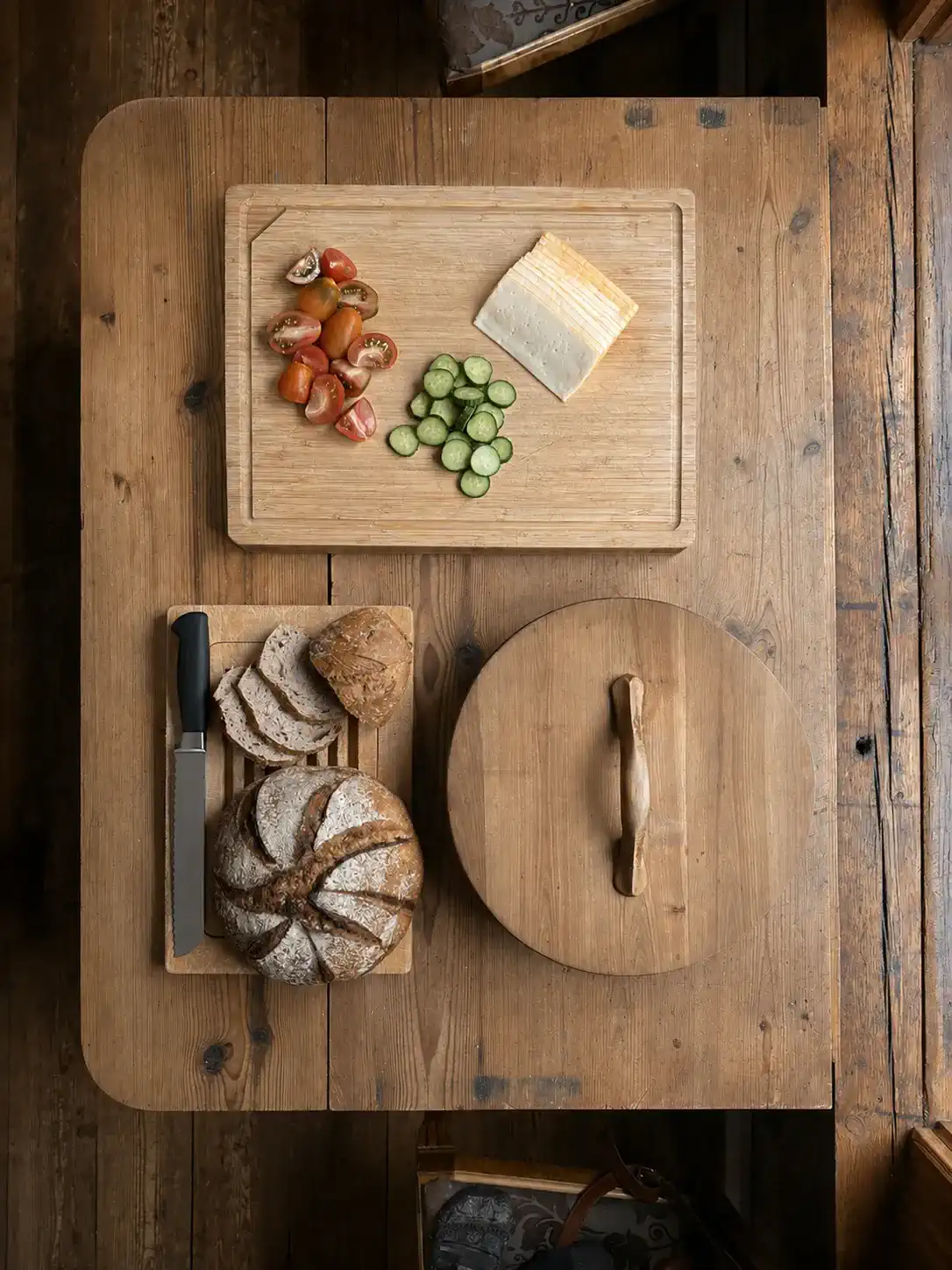 Une table en bois dressée avec du pain frais, du fromage et des légumes.