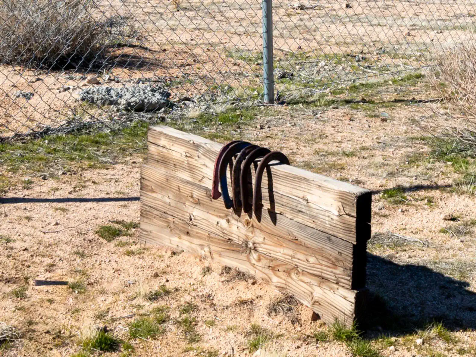Wooden beam with belts resting on it in a sandy outdoor area