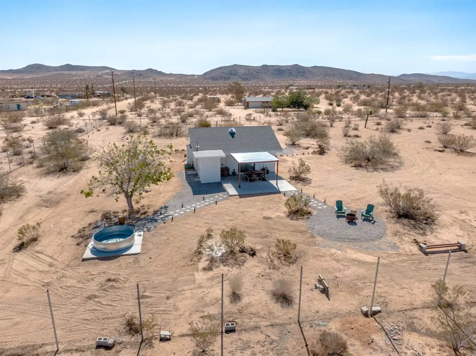 Desert landscape with a modern home, outdoor seating, and a hot tub