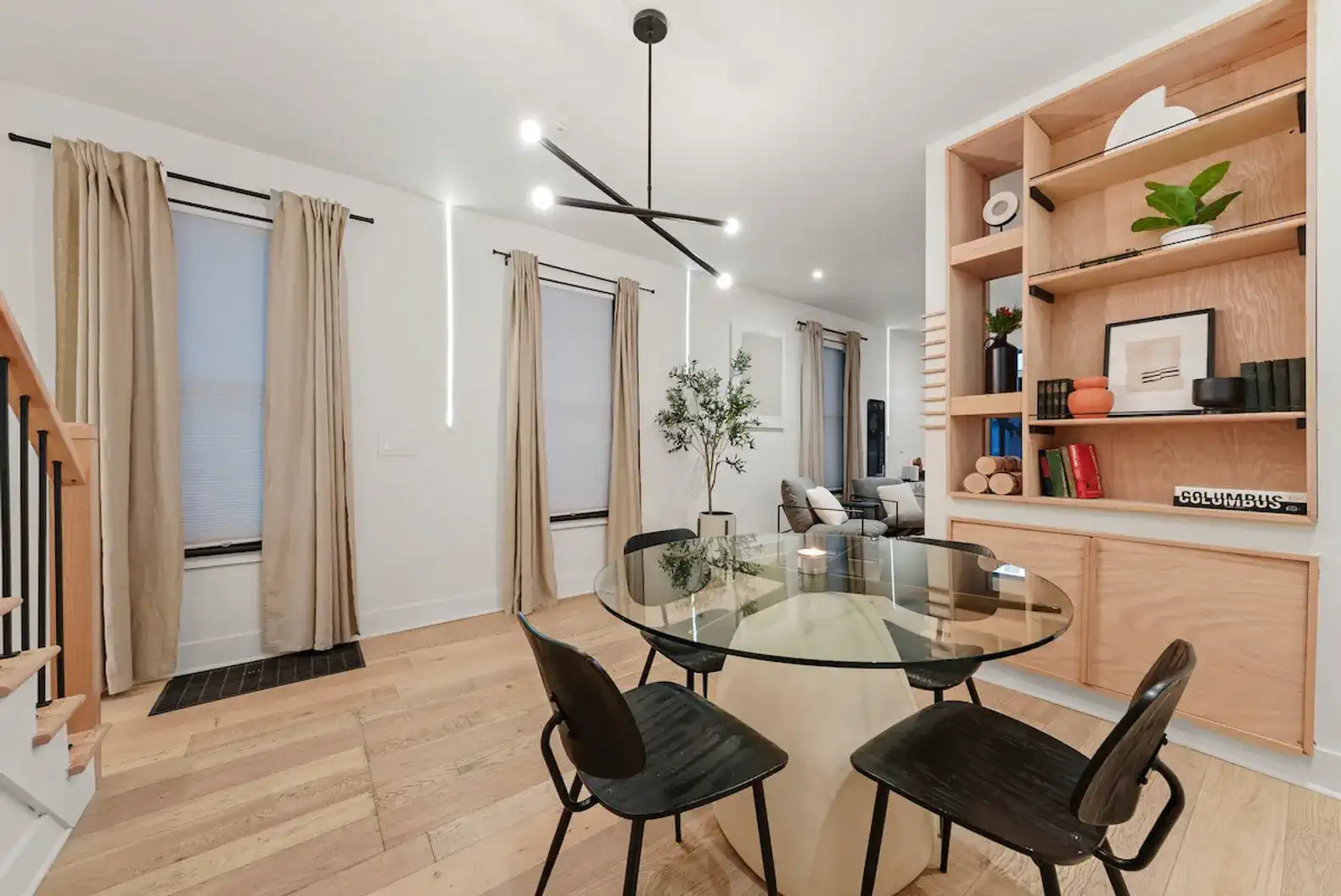 Stylish dining area with modern table and chairs, featuring large windows and decorative shelving