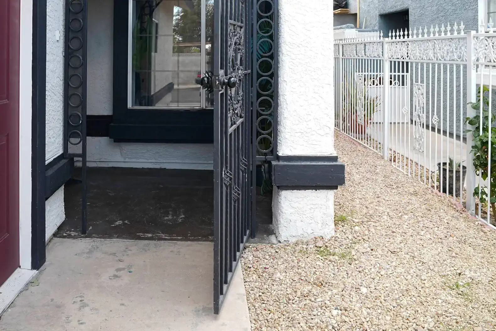 Entrance with decorative gate leading to a gravel pathway