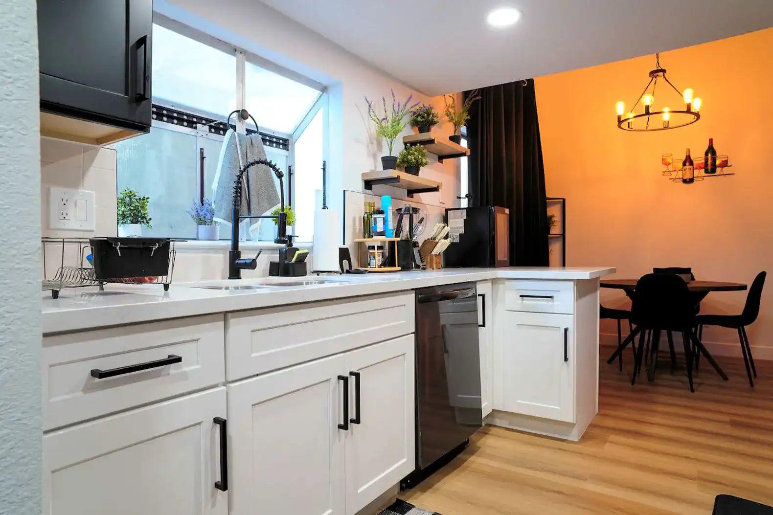 Modern kitchen with white cabinets, stainless steel appliances, and dining area