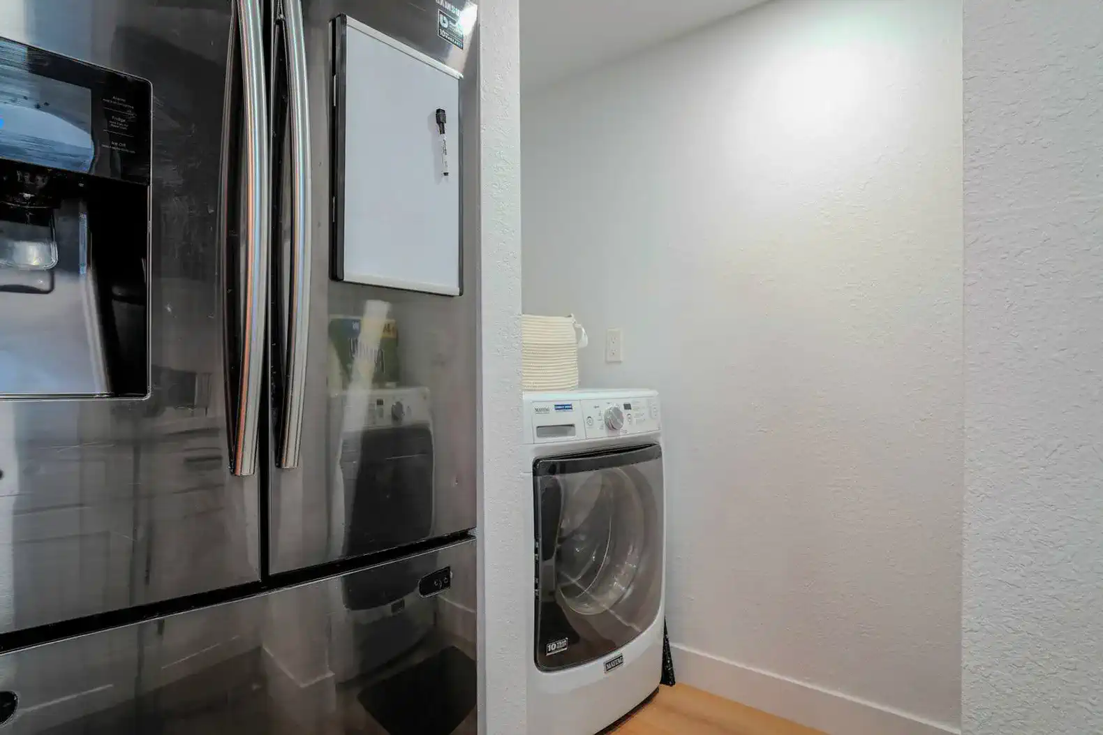 Laundry area featuring a washing machine next to a stainless steel refrigerator