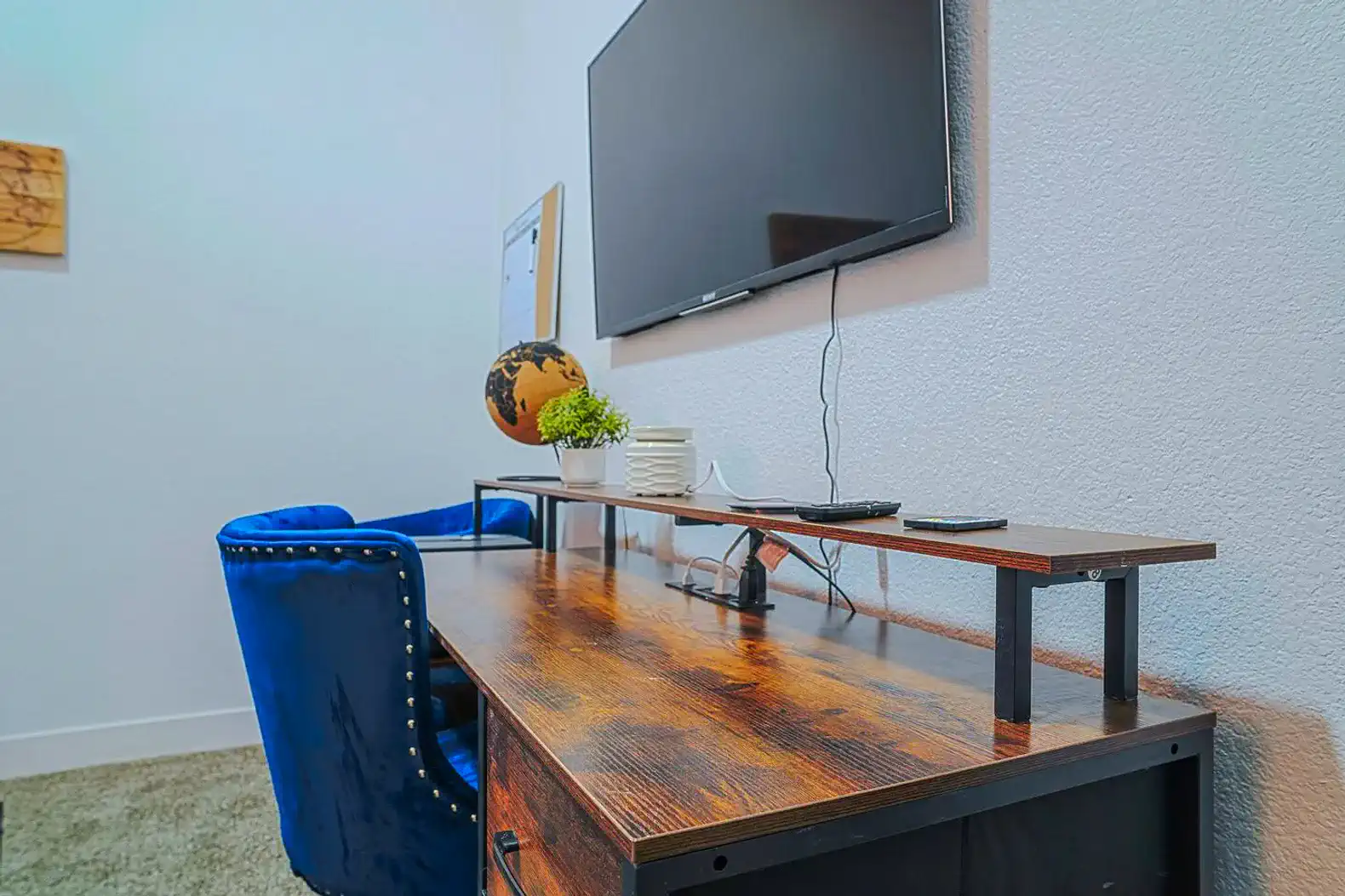 Cozy office space with a wooden desk, blue chair, and wall-mounted TV
