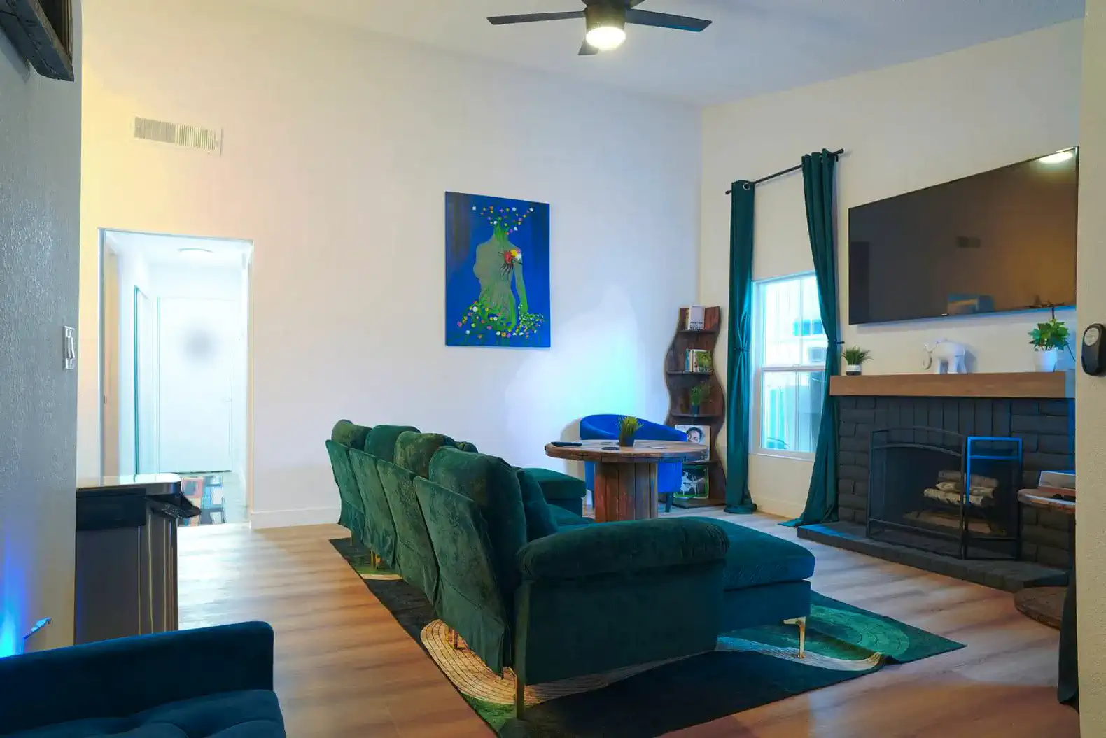 Cozy living room with green sofas, a fireplace, and a large TV