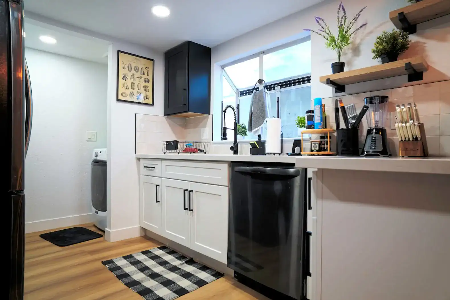 Modern kitchen with sleek appliances, white cabinets, and a window view