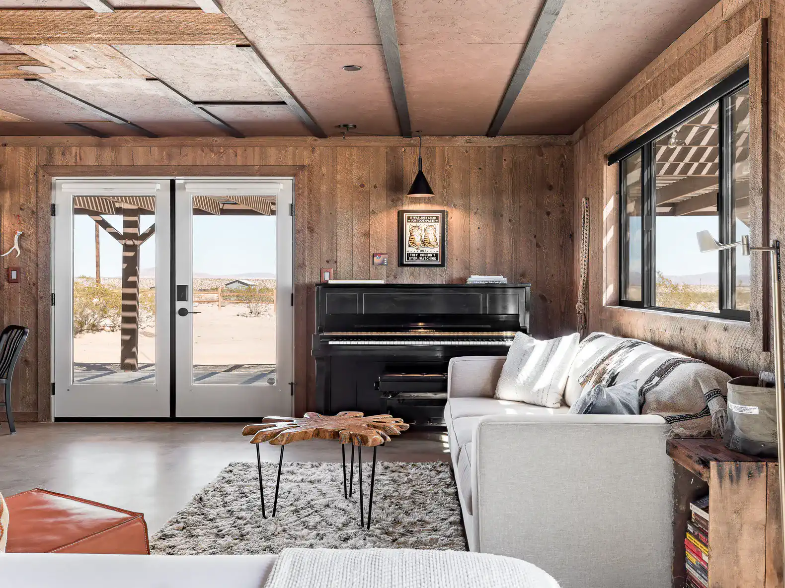 Cozy living room with a piano, modern sofa, and rustic wooden walls