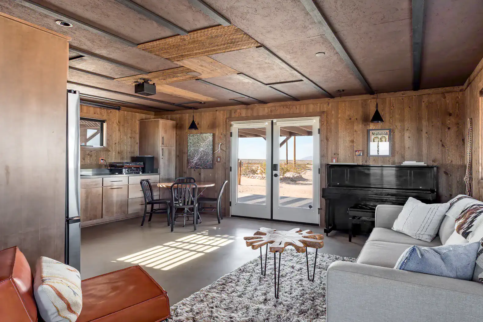 Cozy living area with a piano, dining table, and large windows showcasing desert views