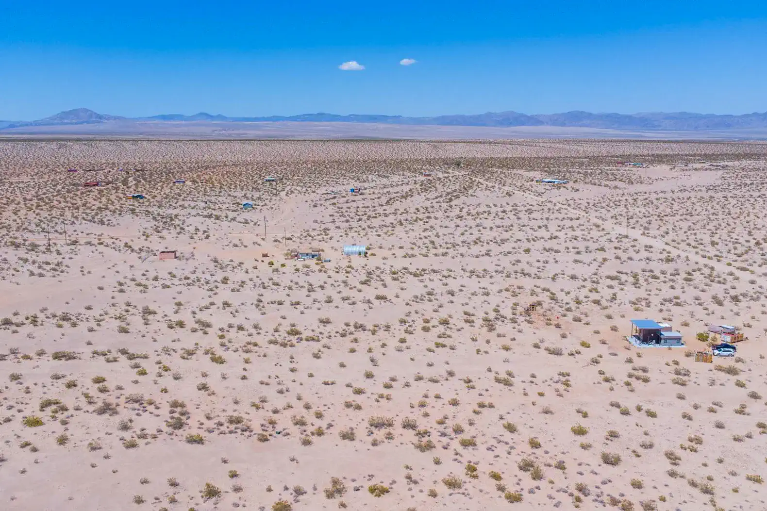 Aerial view of a vast desert landscape with scattered structures and sparse vegetation