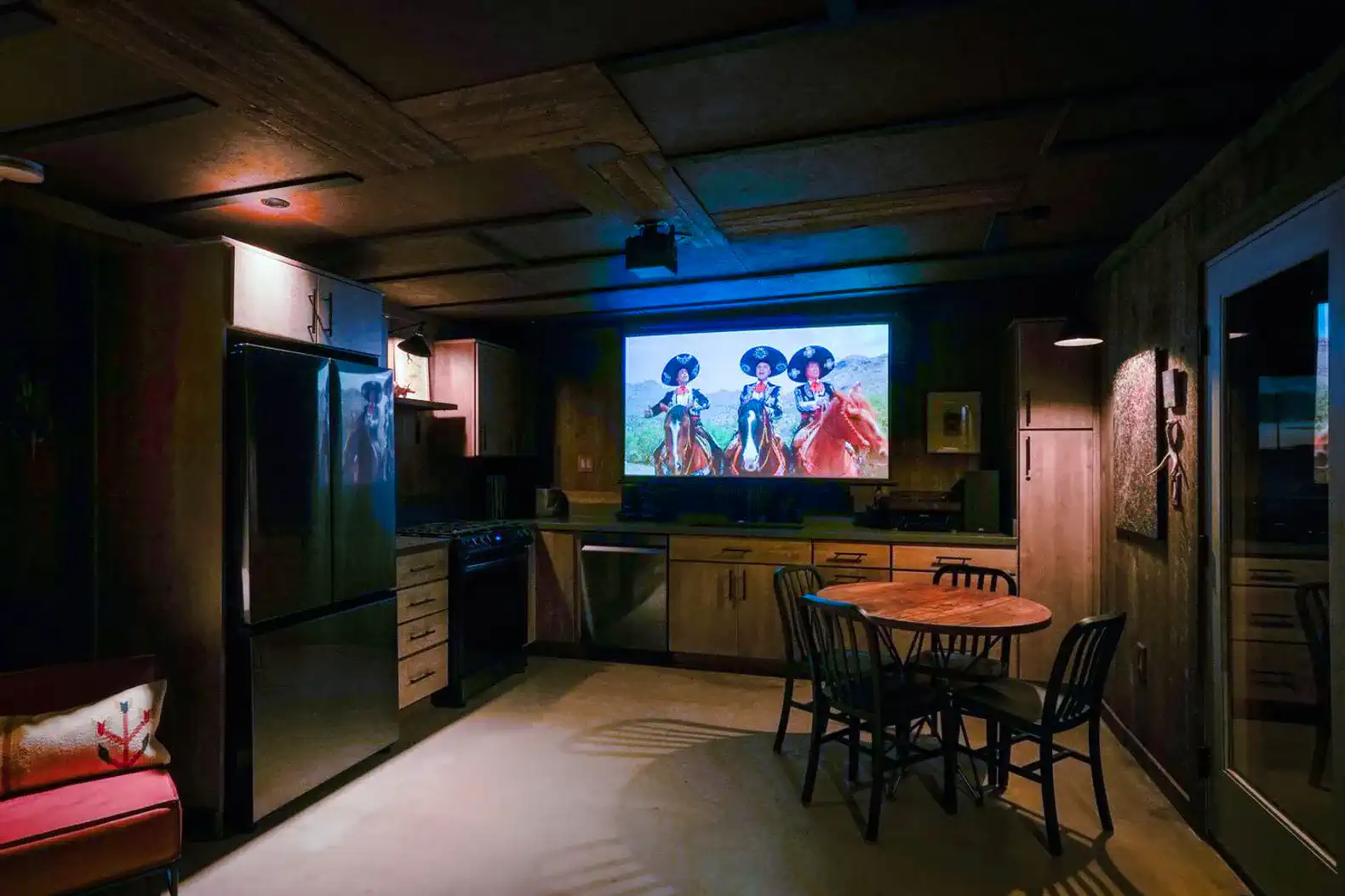Modern kitchen with a dining table and a projector screen displaying a movie