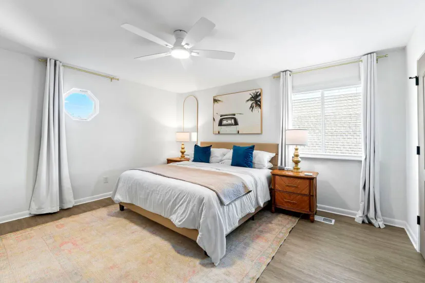 Chambre principale lumineuse et aérée avec un lit queen, lampes décoratives et une fenêtre