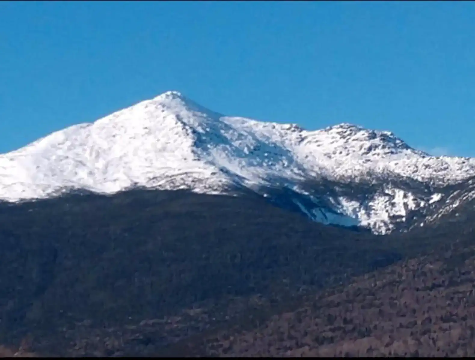 Snow-capped mountain peak against a clear blue sky