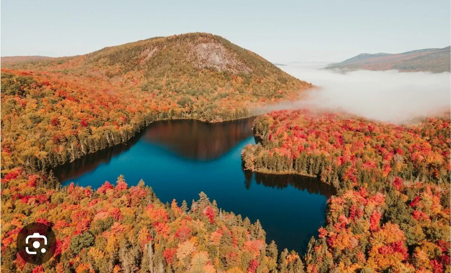 Aerial view of a vibrant autumn landscape with a lake surrounded by colorful fall foliage