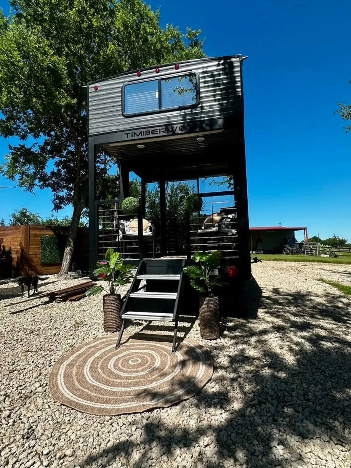 Stylish tiny home exterior with steps, surrounded by greenery and gravel