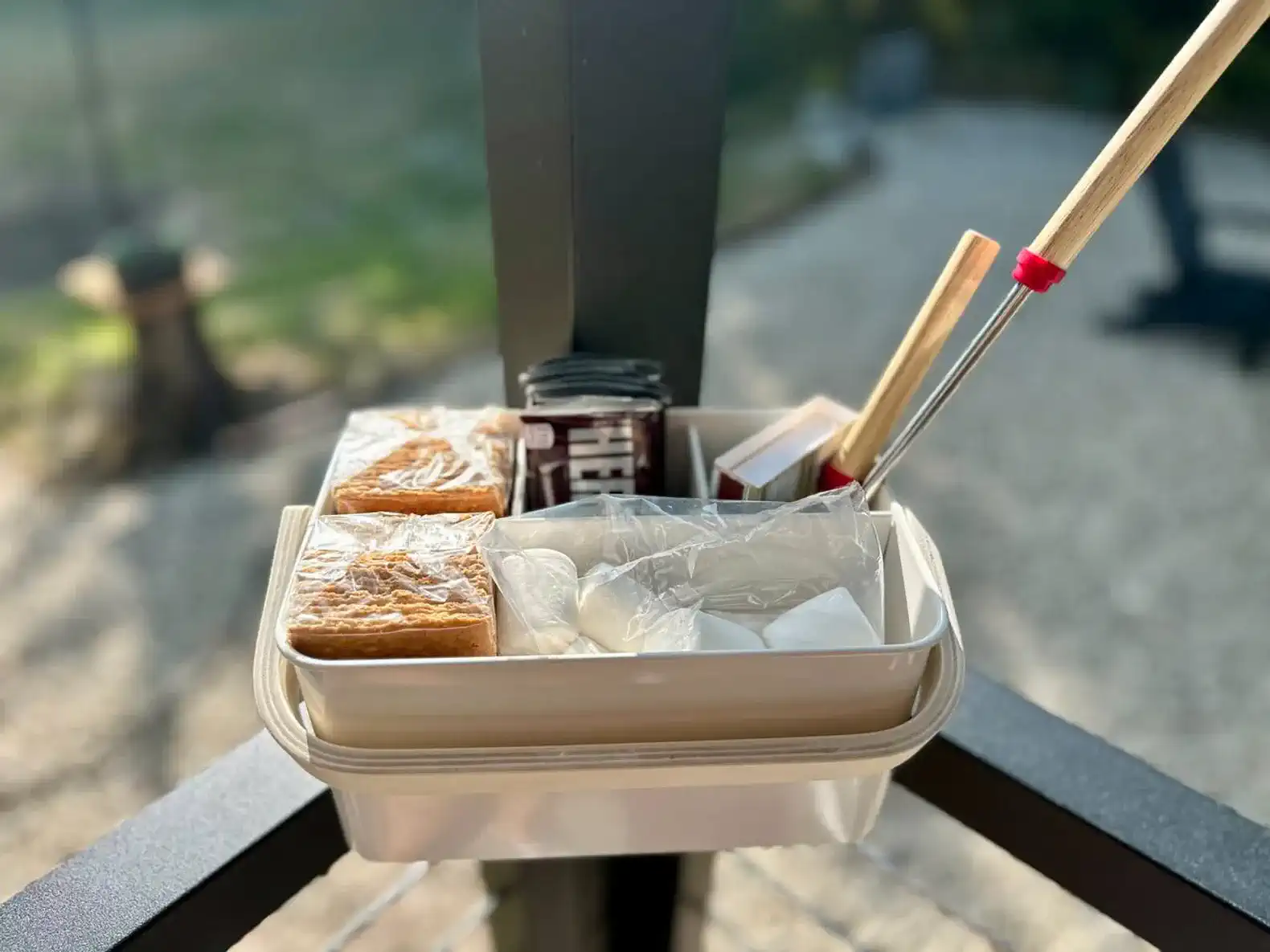 Outdoor snack basket with treats and utensils on a patio railing