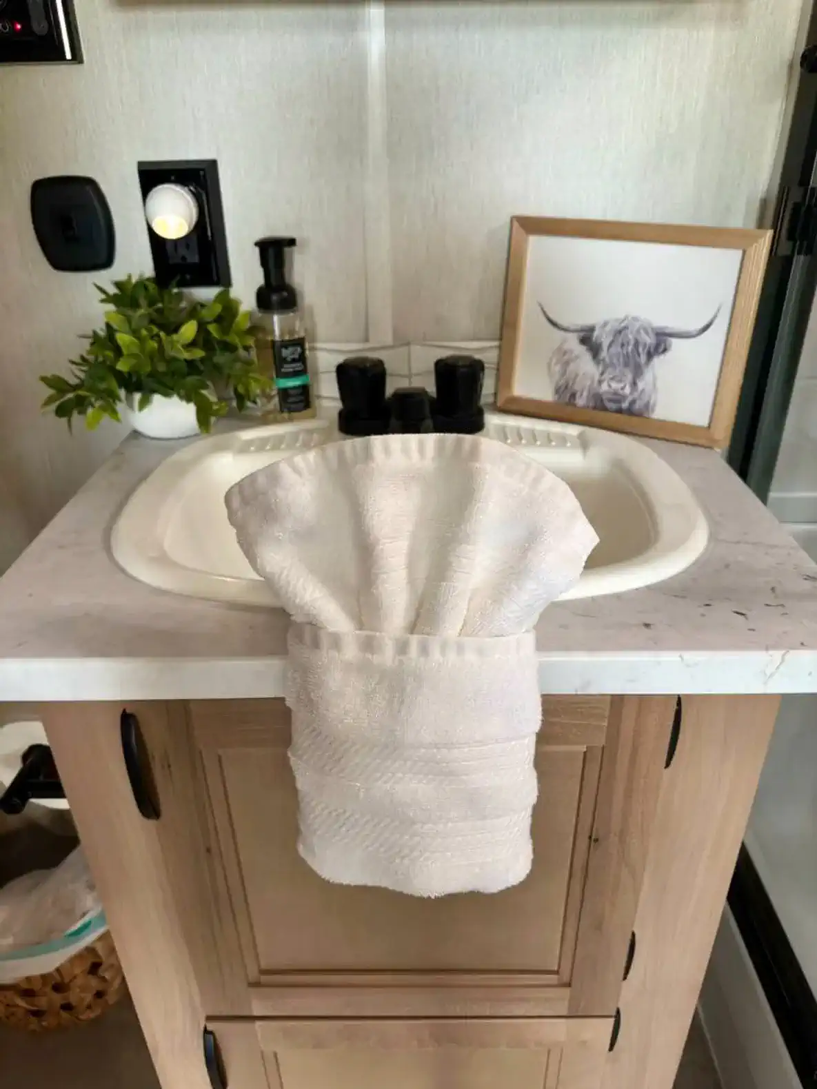 Stylish bathroom sink with a white towel and decorative plant