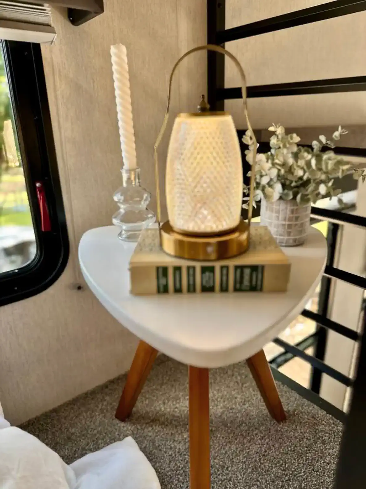 Cozy bedside table with a lantern, decorative flowers, and books