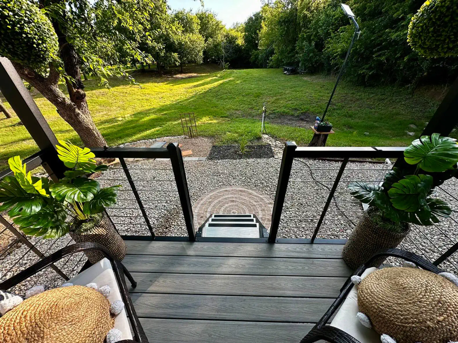 View from the patio showing a lush green yard and trees