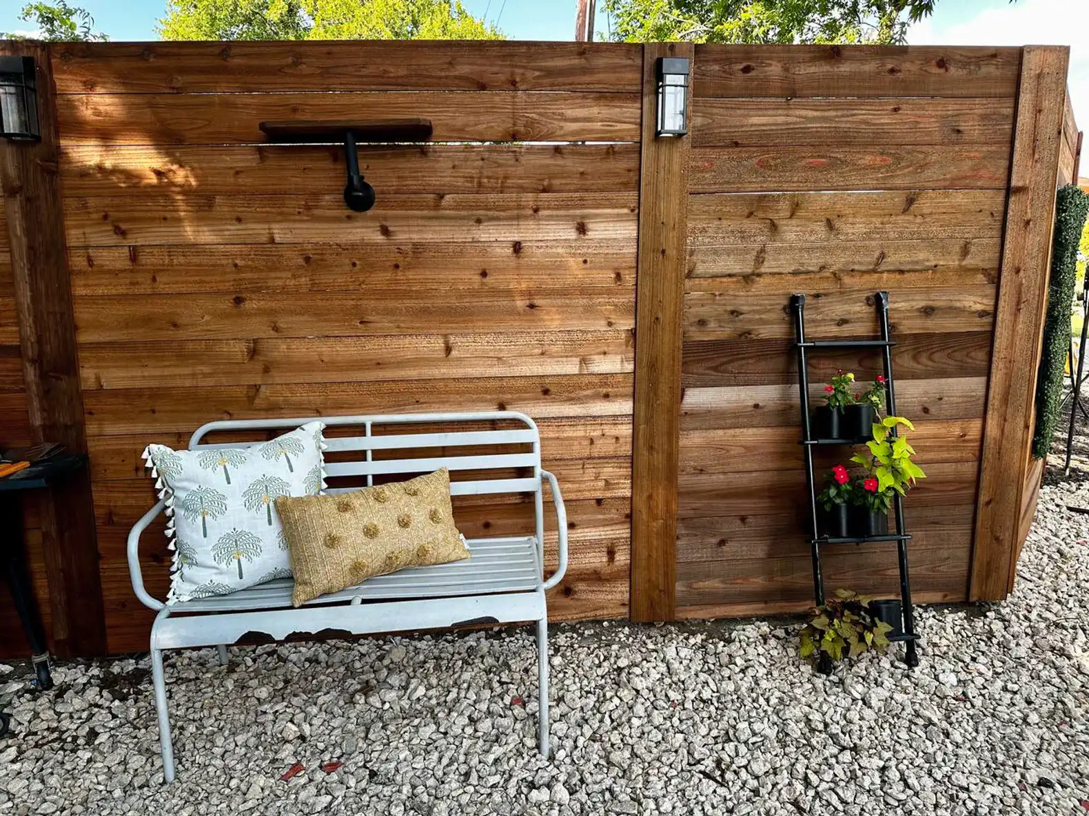 Cozy outdoor seating area with a bench and decorative pillows against a wooden fence
