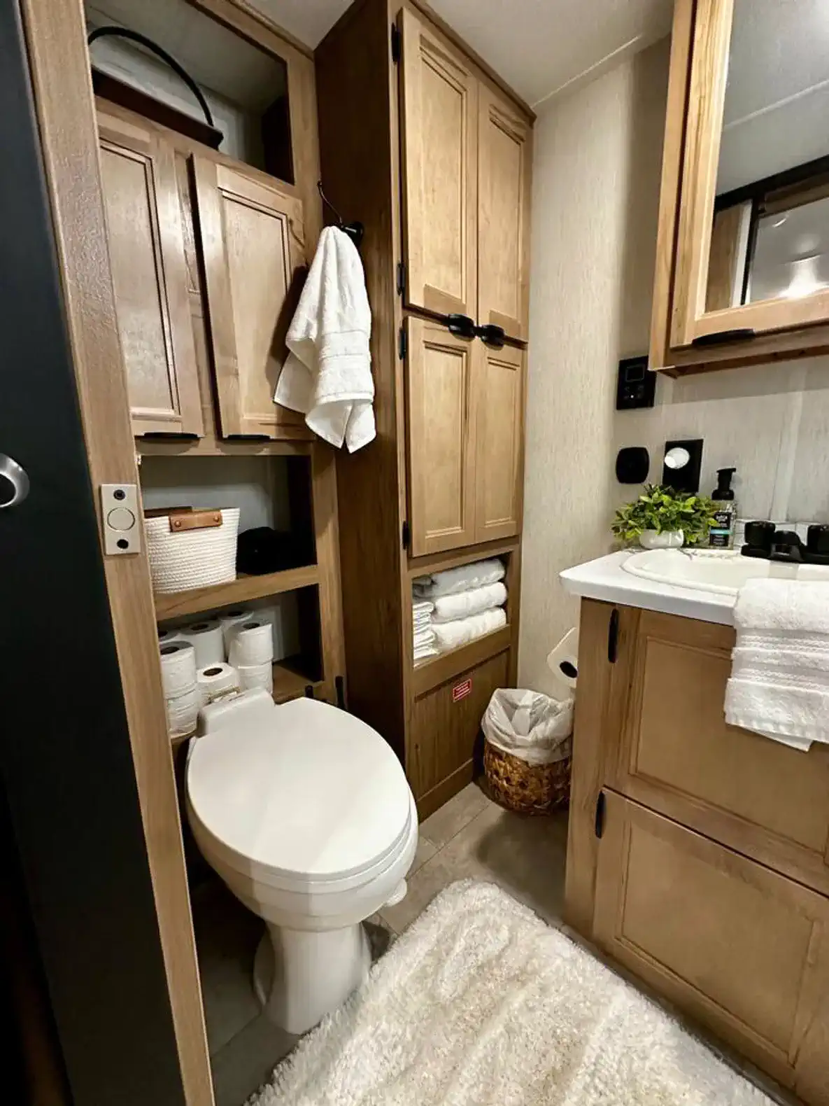Cozy bathroom featuring wooden cabinets, a toilet, and a sink with toiletries