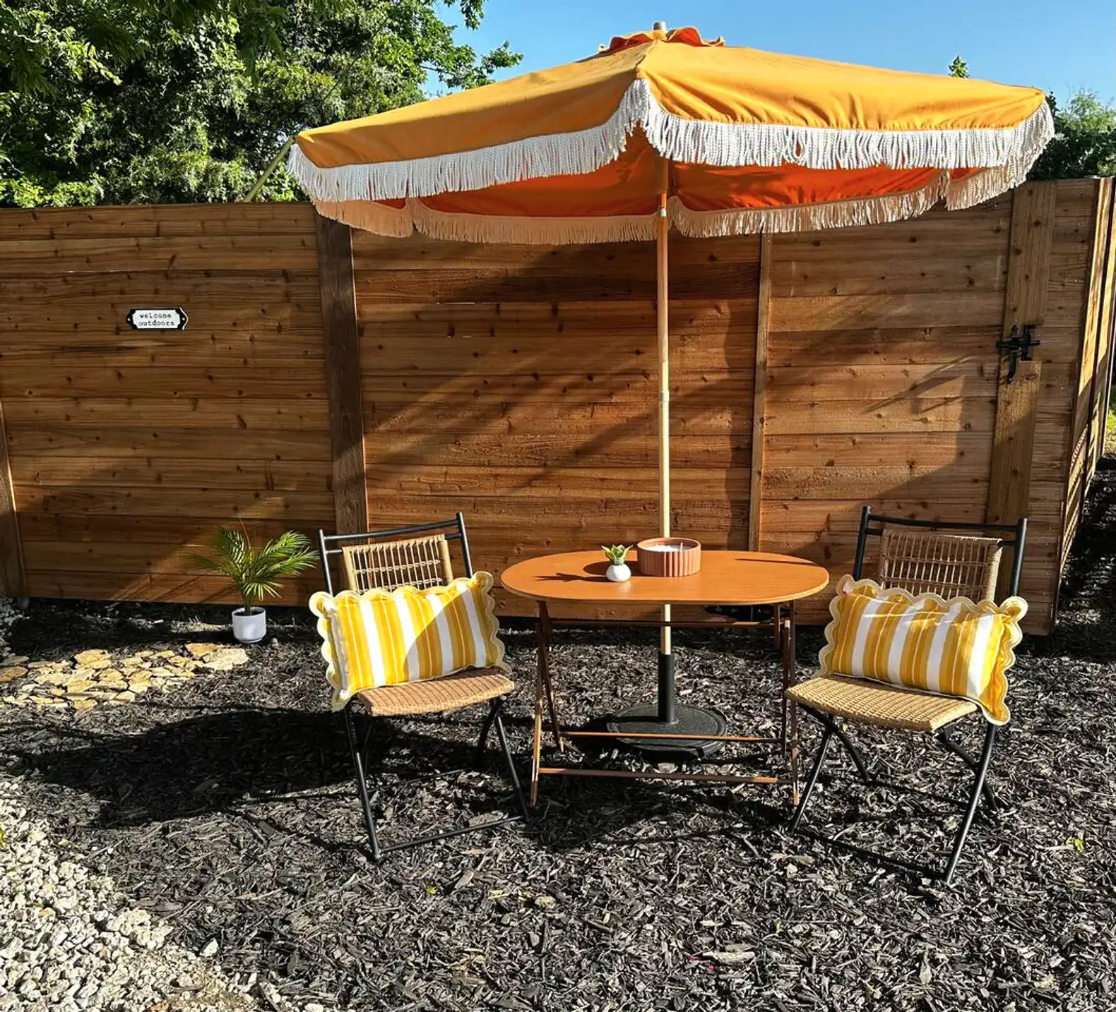 Cozy outdoor seating area with a round table, two chairs, and a vibrant umbrella
