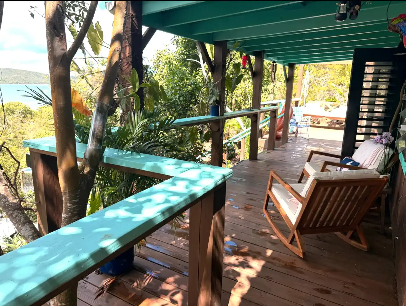 spacious outdoor deck with wooden chairs and lush greenery