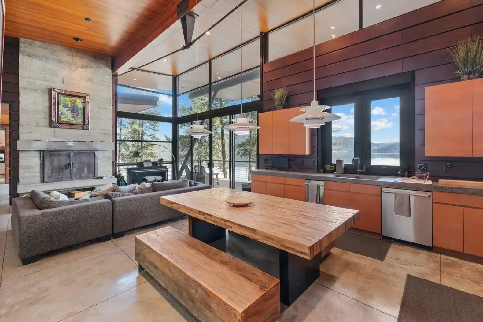 Modern kitchen with wooden dining table and large windows overlooking the forest