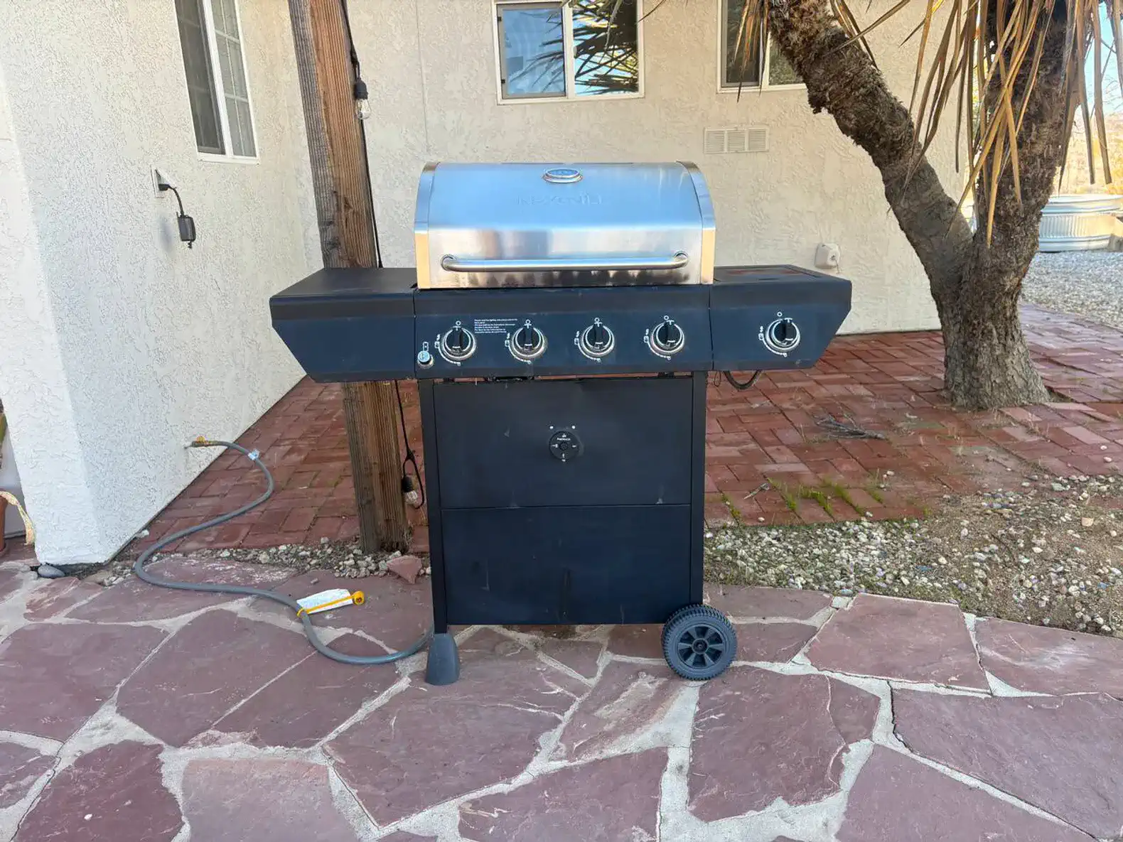 Outdoor grill on a stone patio surrounded by desert landscape