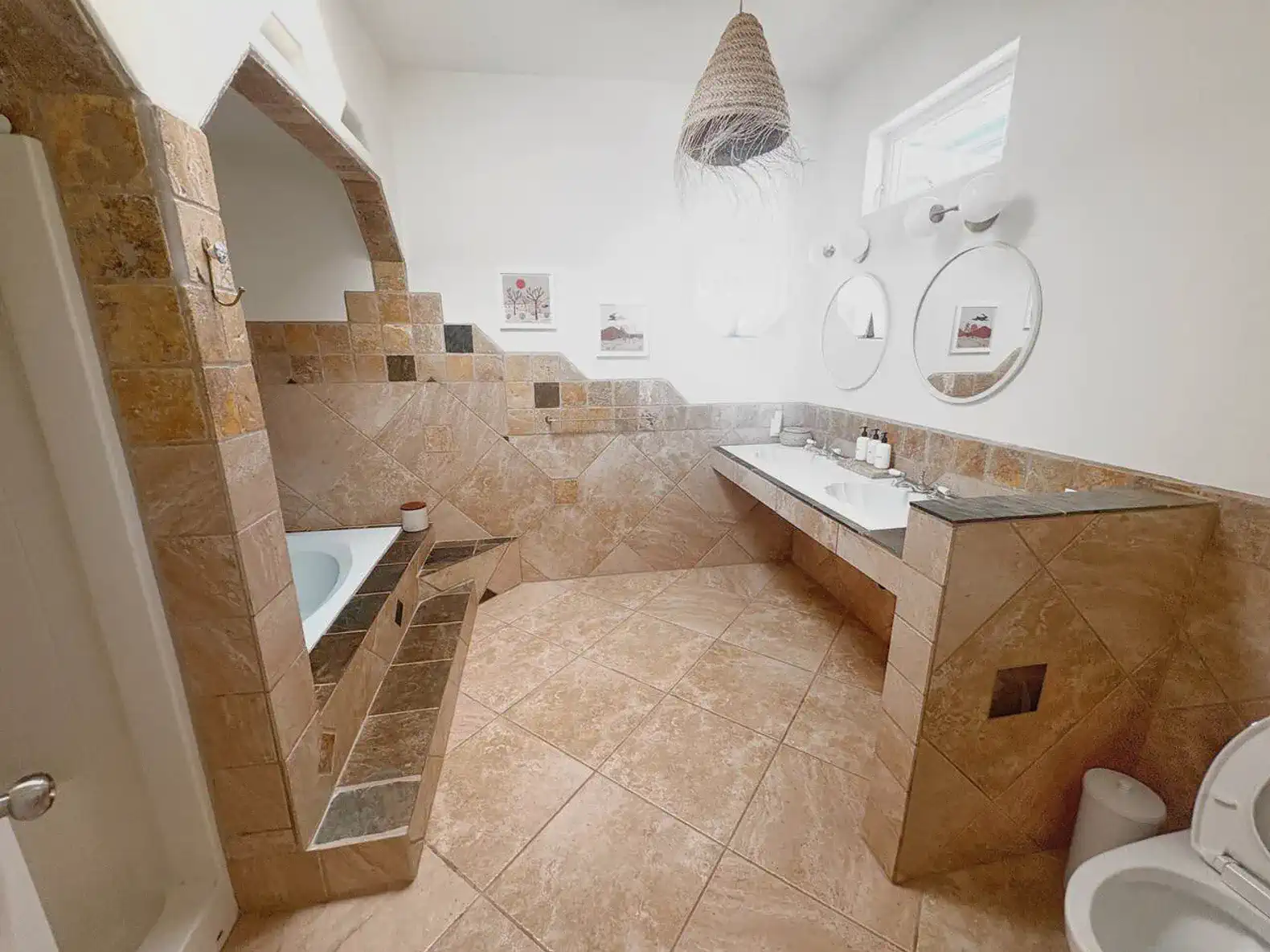 Spacious bathroom with stone tiles, double sink, and a soaking tub