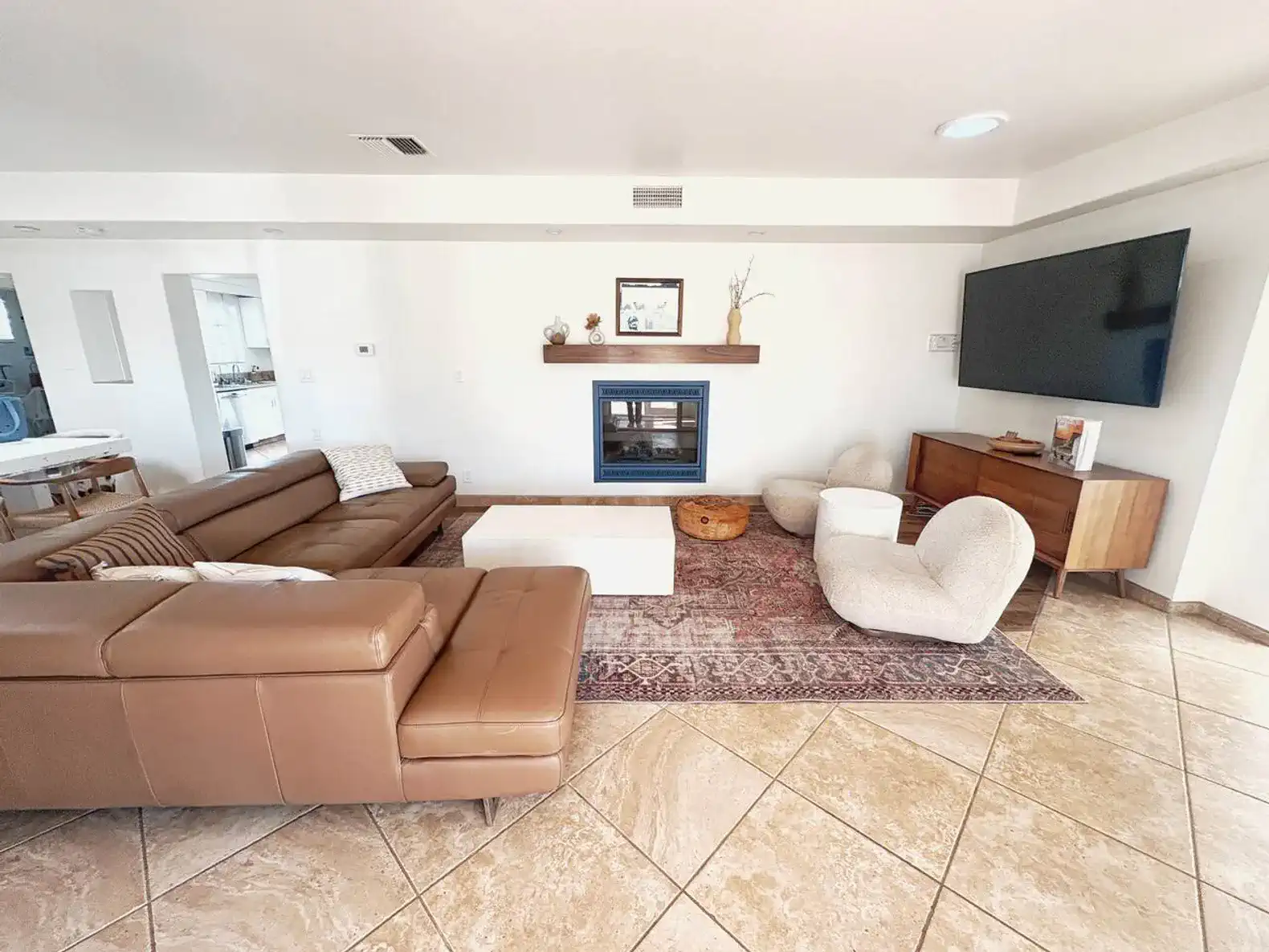 Spacious living room with leather sofas, a fireplace, and a large TV