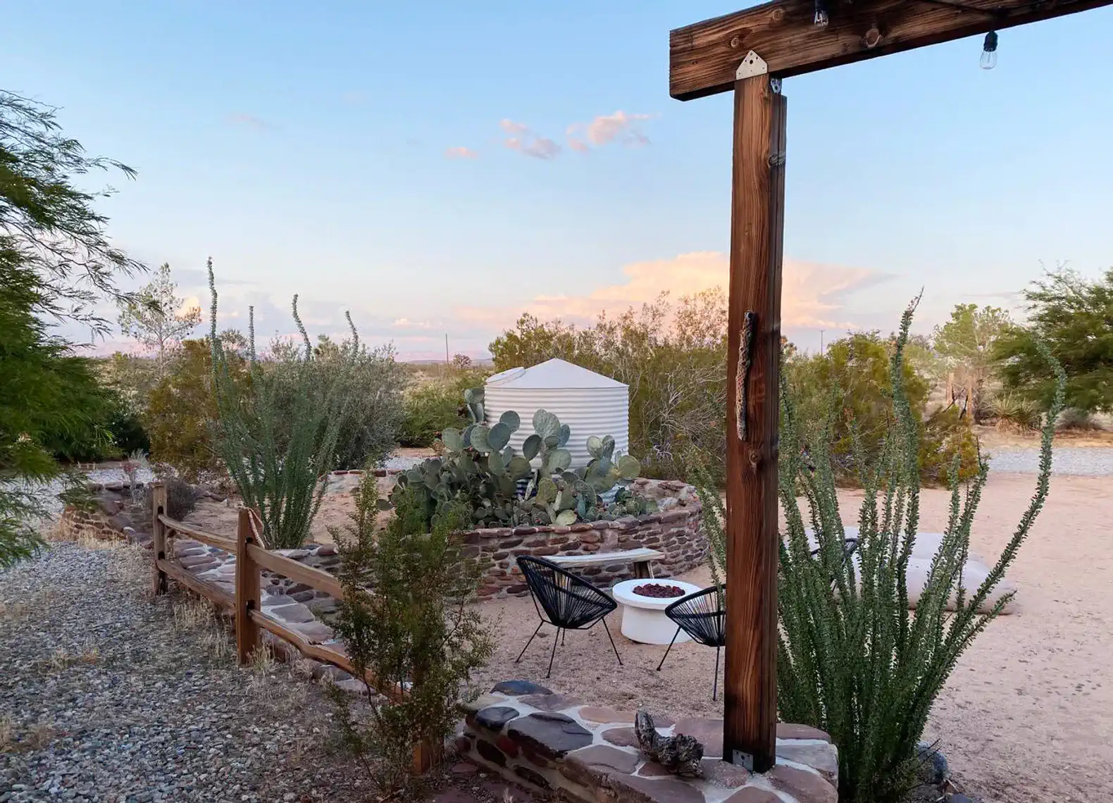 Desert landscape with fire pit, seating area, and cacti surrounded by greenery