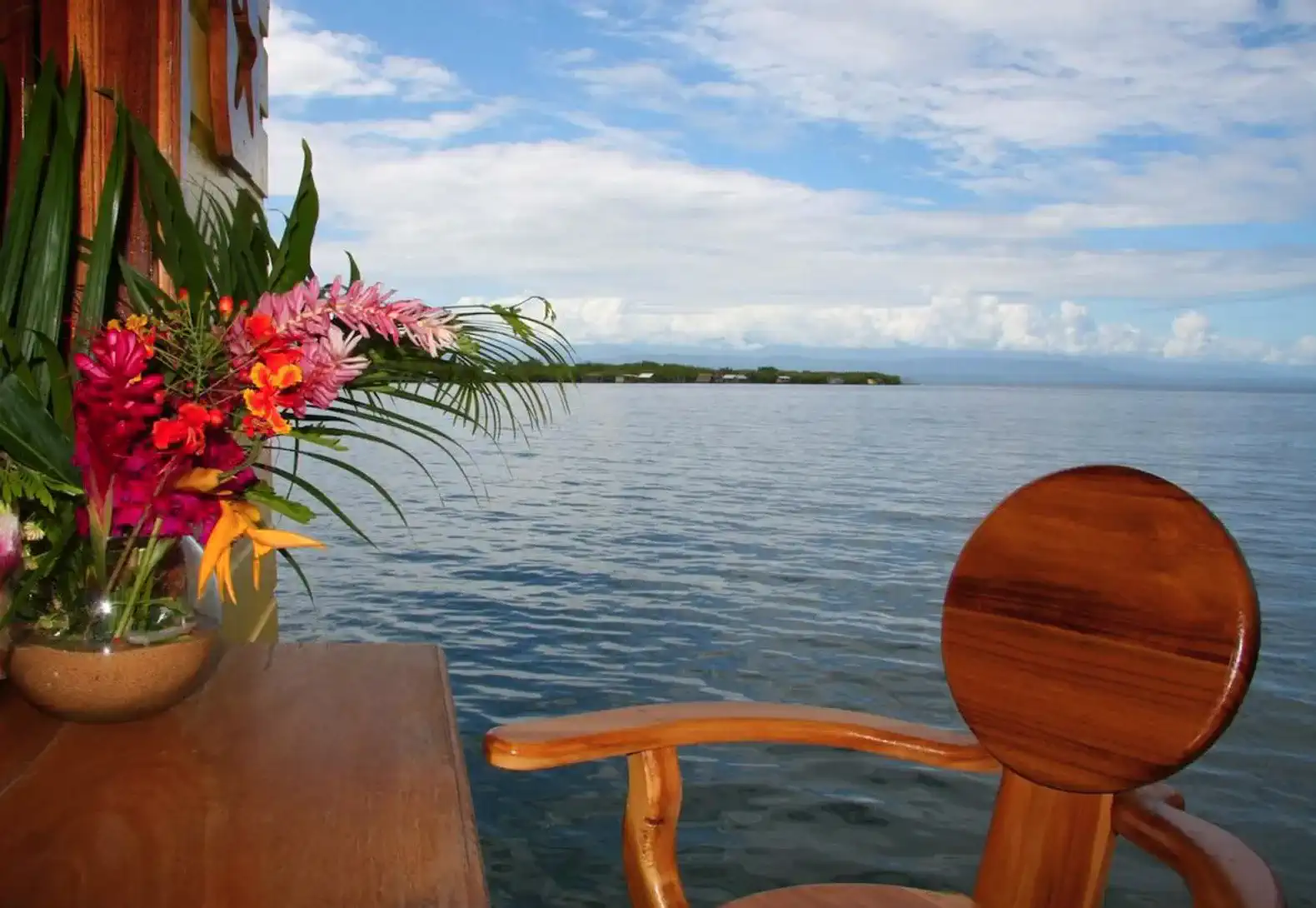View of the sea from a wooden chair with tropical flowers in the foreground
