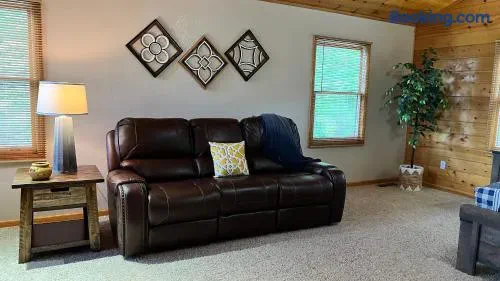 Cozy living room with a brown leather sofa, decorative wall art, and natural light from windows