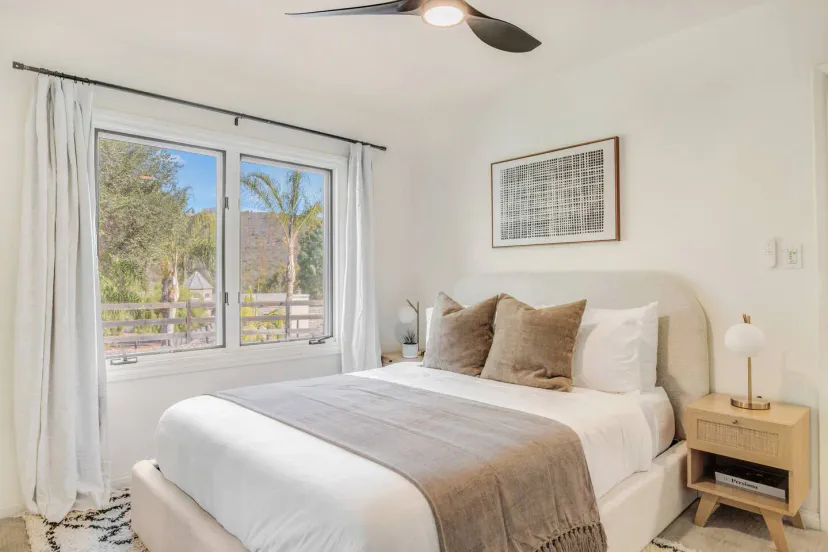Cozy bedroom with a queen bed, natural light, and views of palm trees