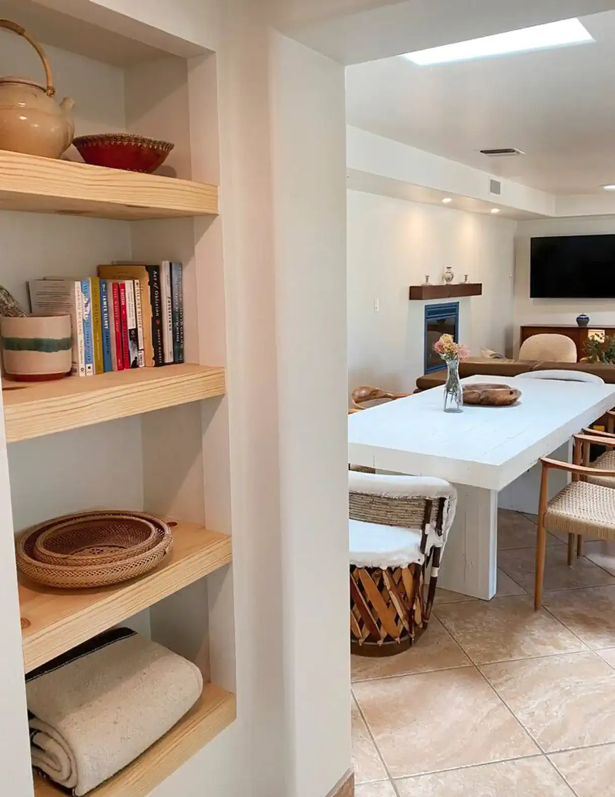 Open dining area with a long table and shelves displaying books and decorative items