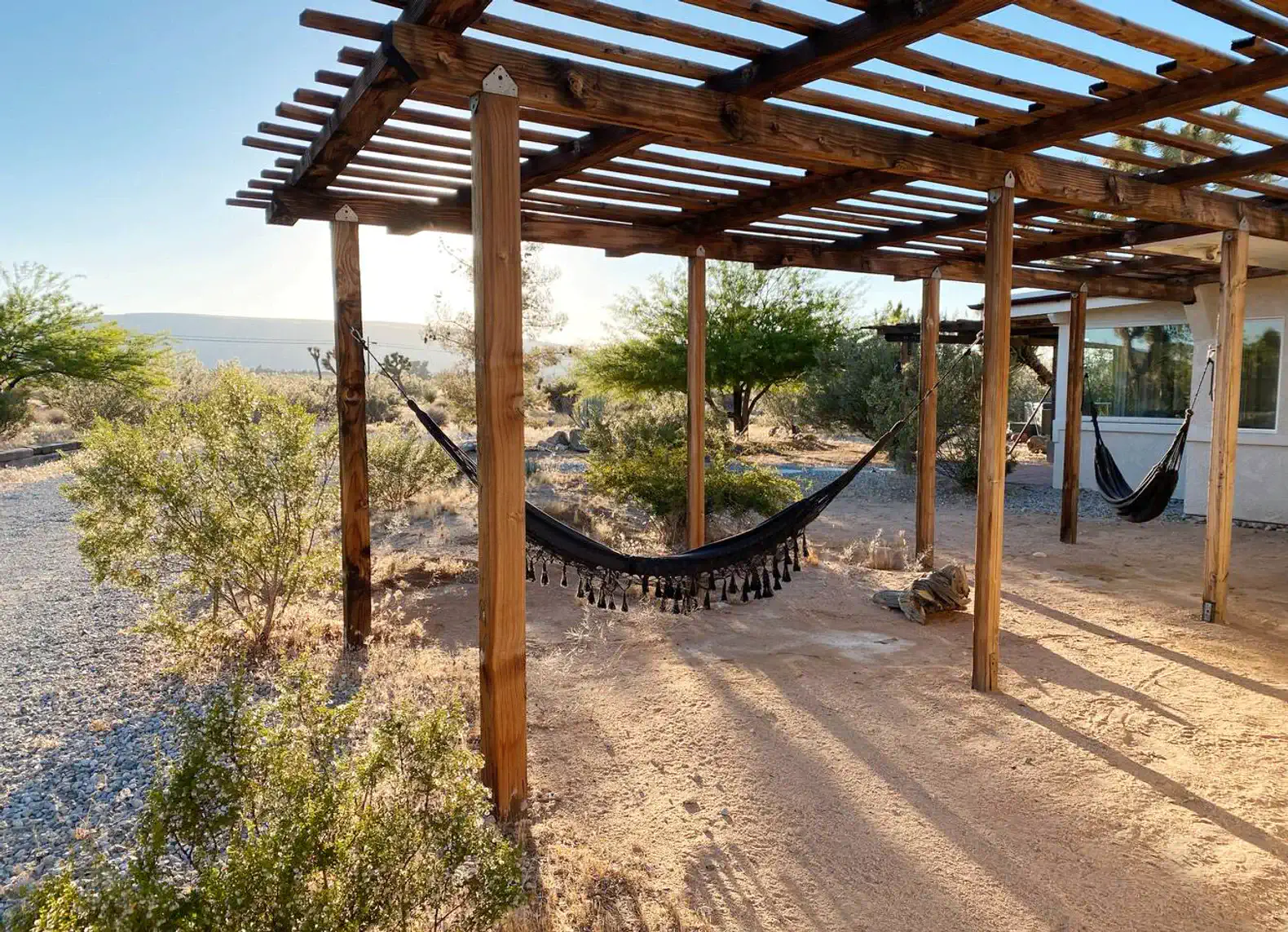 relaxing hammocks under a wooden pergola in a desert landscape