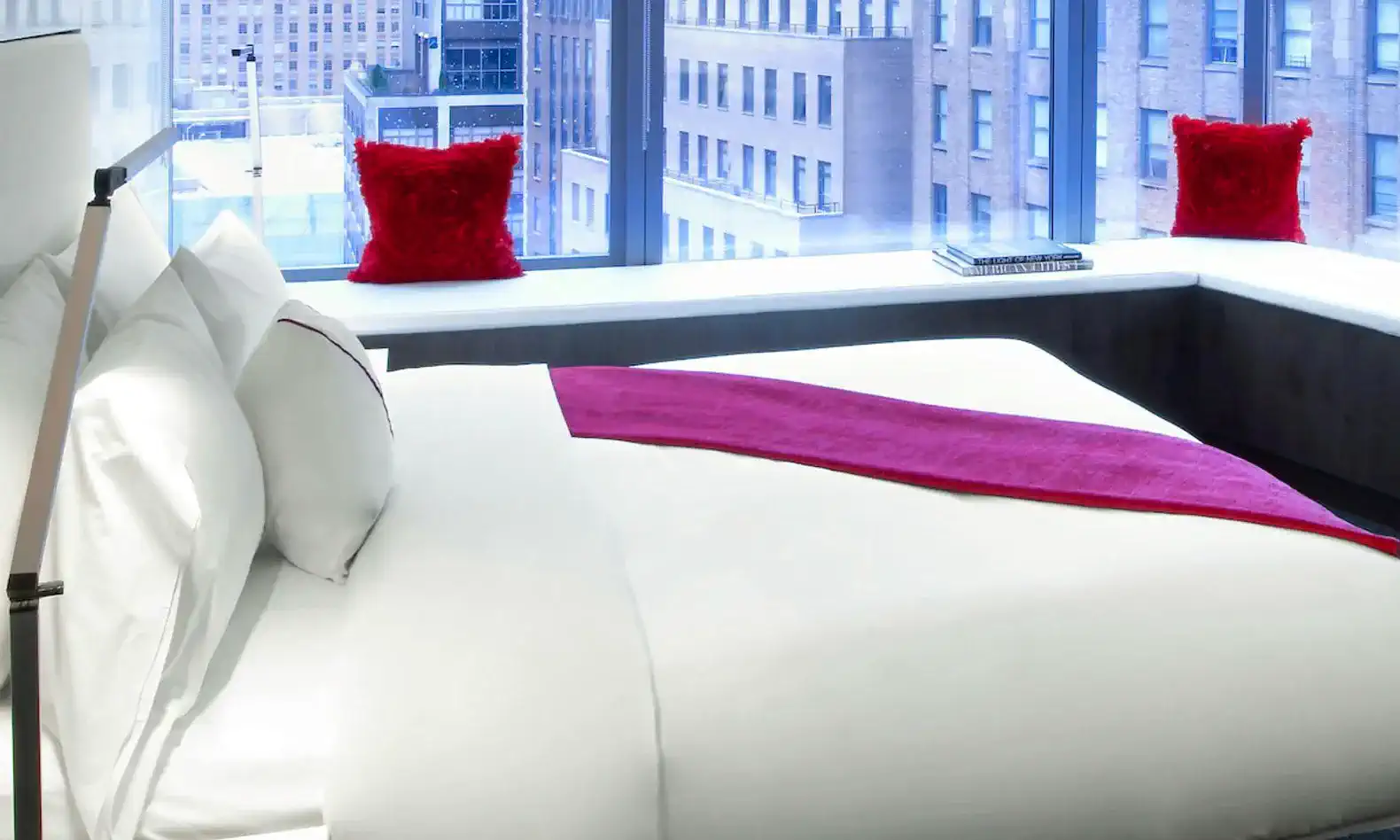 Cozy bedroom with a large bed and city view through large windows