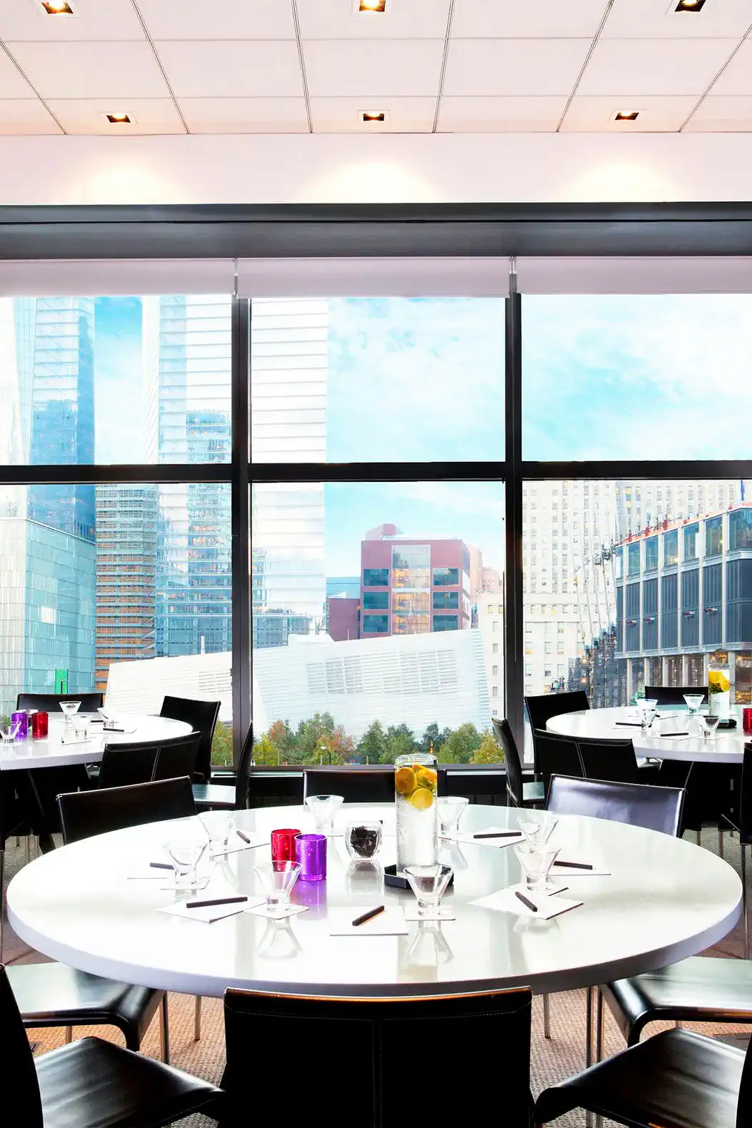 Modern dining area with round tables and large windows showcasing city views