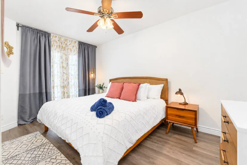 Acogedora habitación principal con cama queen, almohadas decorativas y cortinas elegantes