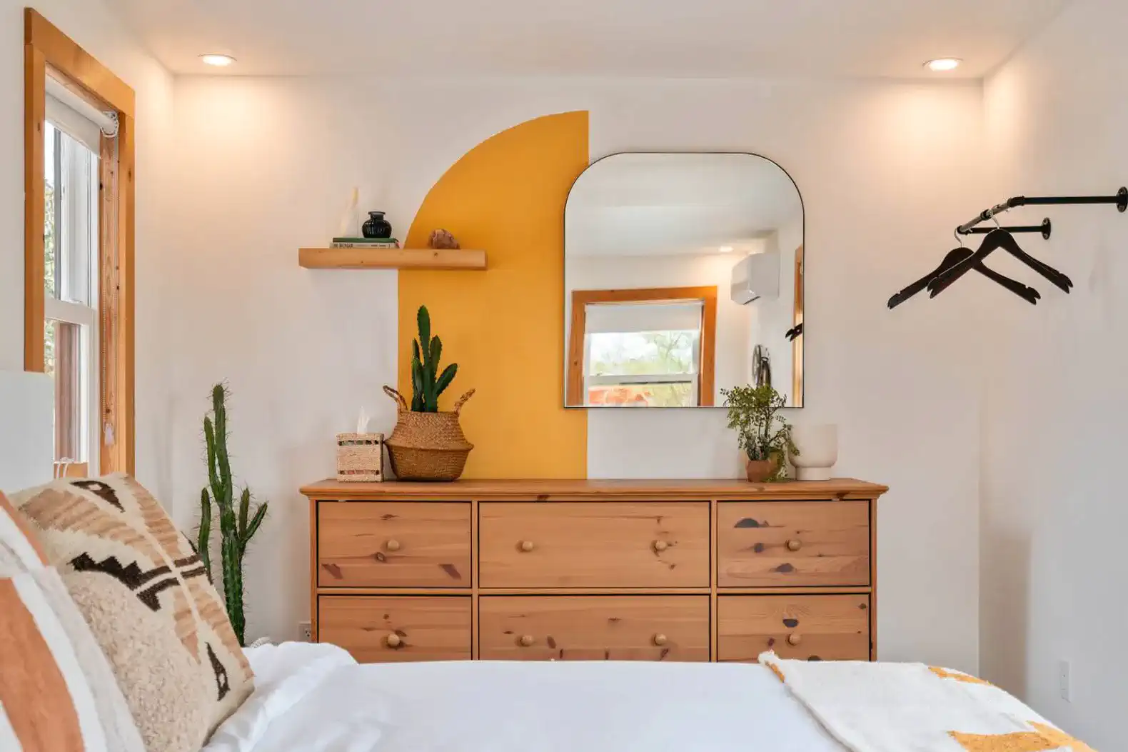 Cozy master bedroom with wooden dresser, mirror, and decorative plants