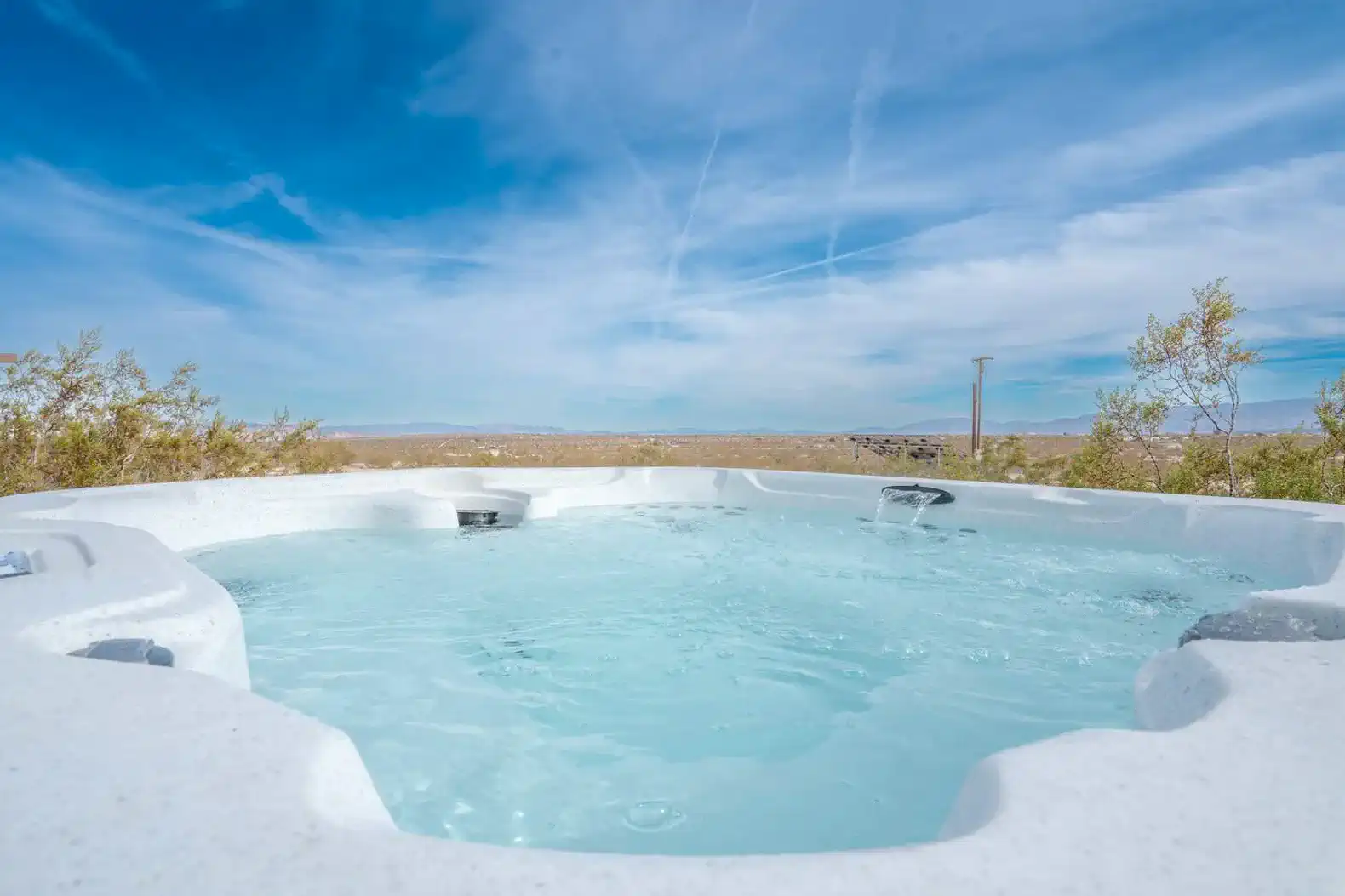 Hot tub with clear water overlooking desert landscape and blue sky