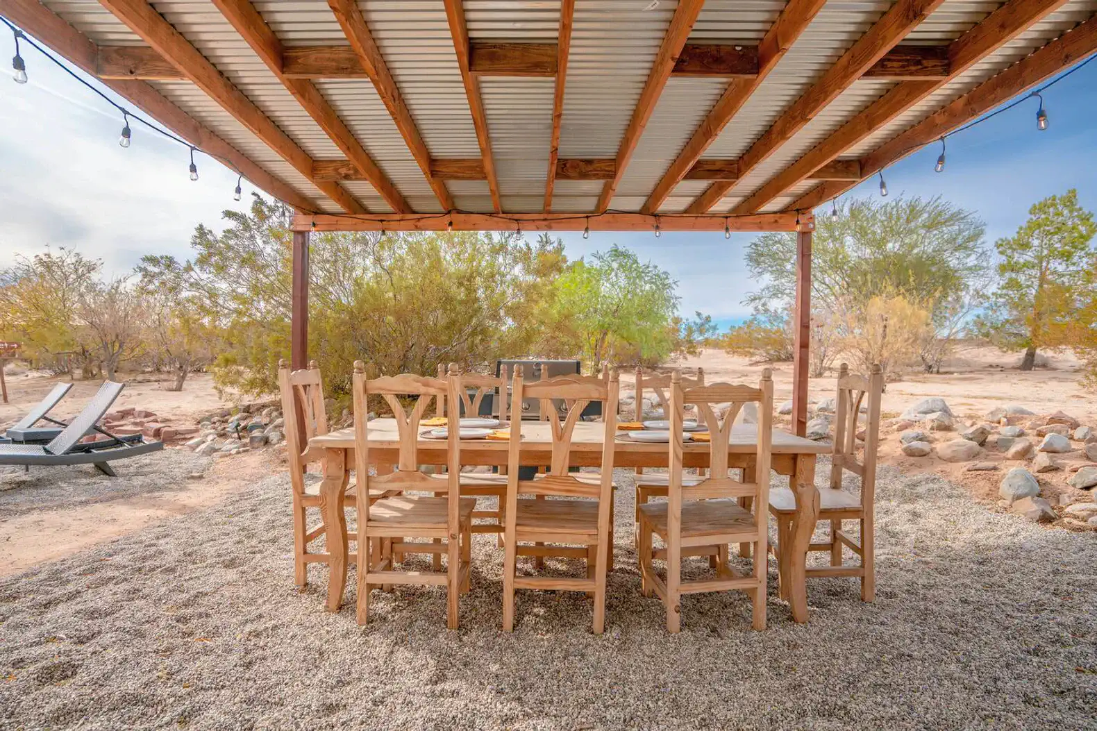 Spacious outdoor dining area with wooden table and chairs under a covered patio