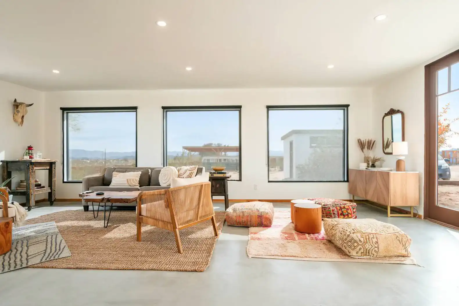 Bright living room with large windows, cozy seating, and decorative rugs