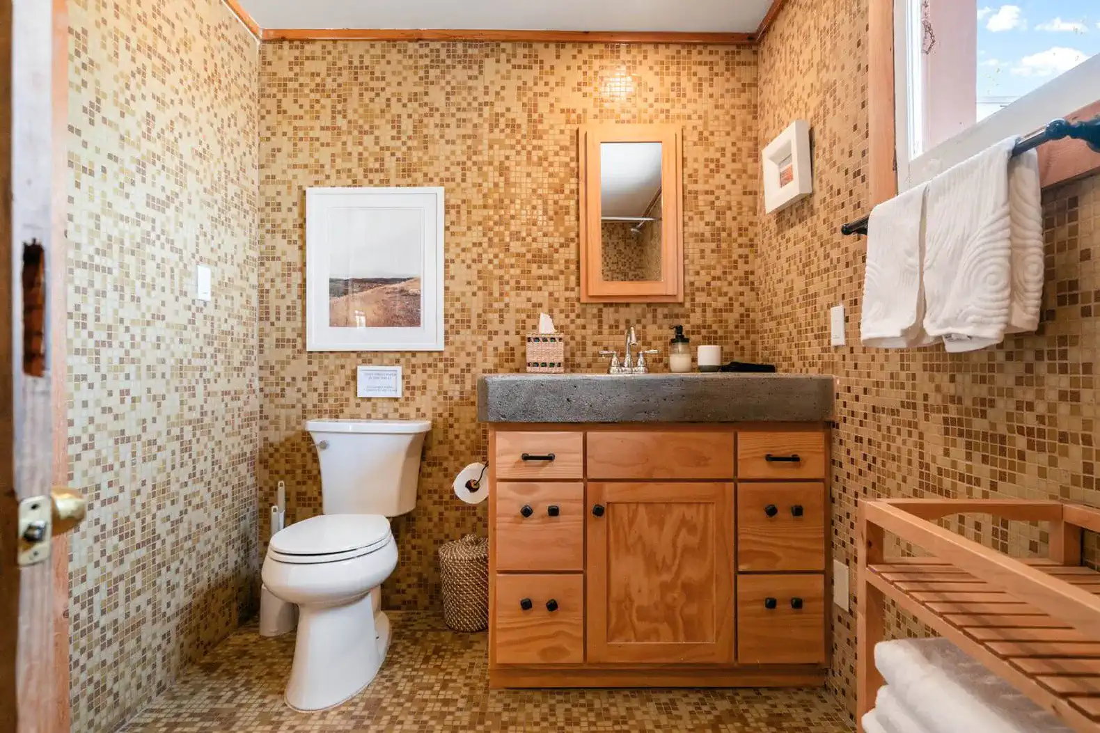 Stylish bathroom with mosaic tiles, wooden cabinetry, and modern fixtures